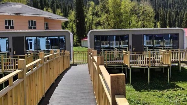 A row of cabins with wooden railings, a wooden walkway, and a mountain backdrop. - Aketasi Resort (Nilka County)