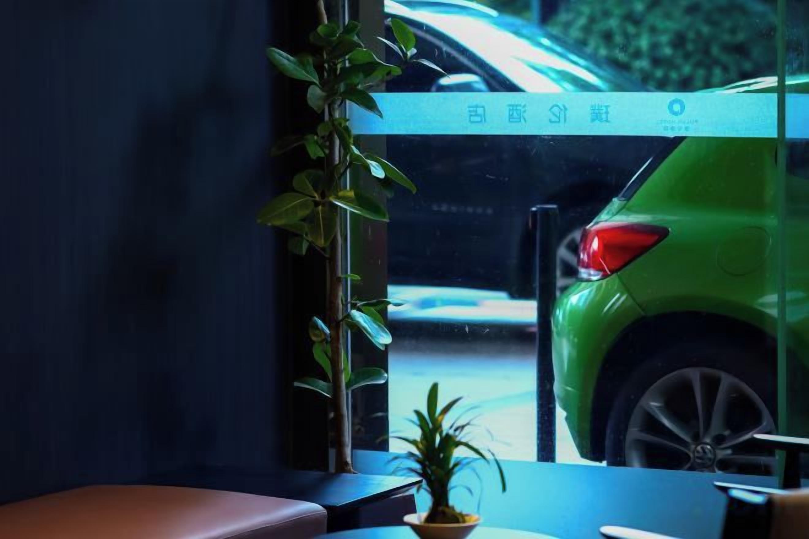 Una ventana con vista a un coche verde en la calle.