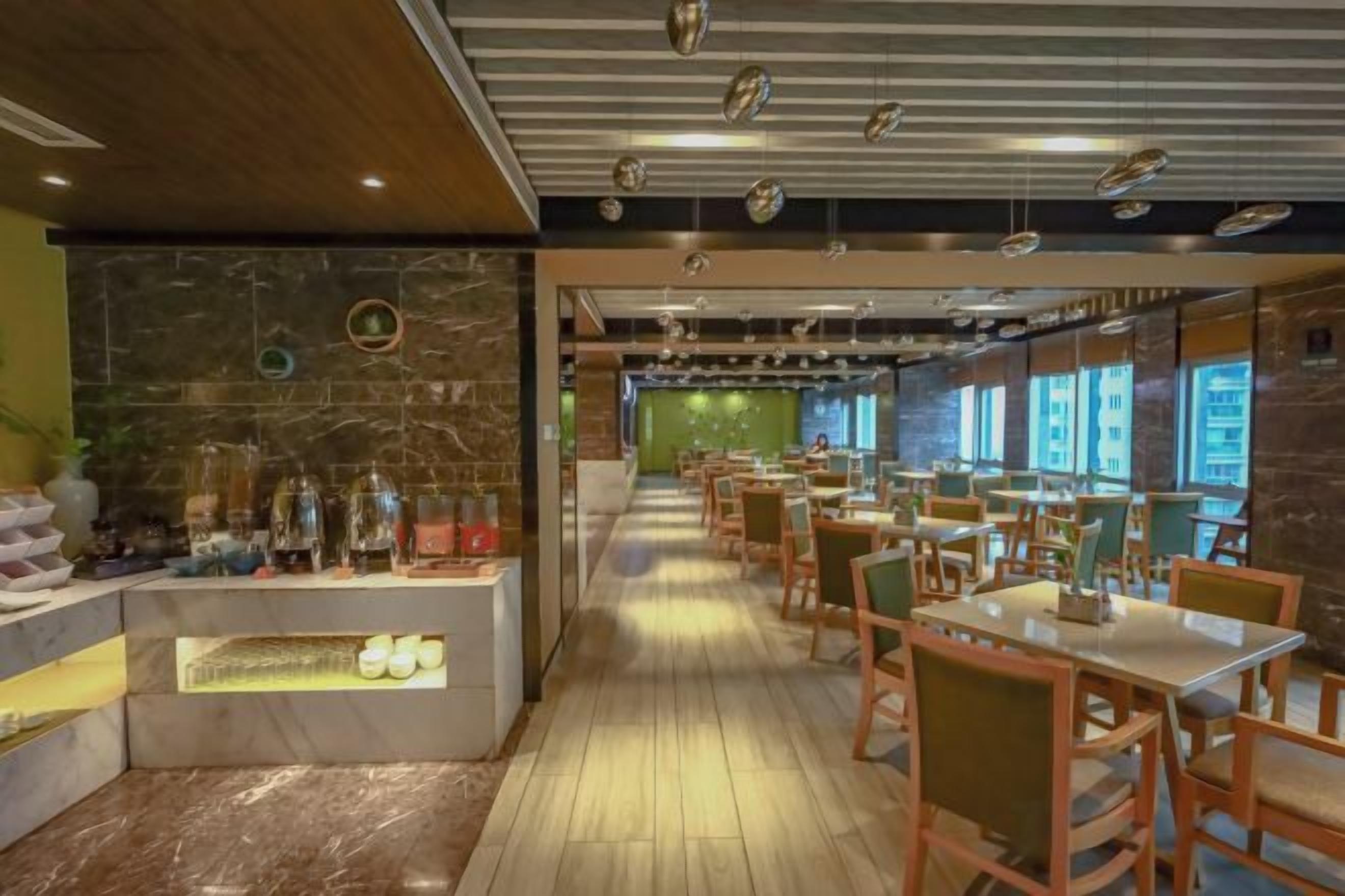 A restaurant interior with a long counter, wooden flooring, and multiple tables and chairs.