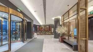 A modern hotel lobby with glass doors, a reception desk, and a decorative white floral arrangement. - Pulun Hotel (Shaoxing Didang Shimao Plaza) (Shaoxing)