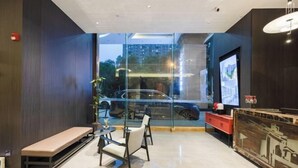 A modern interior with a bench, chairs, a TV, and a glass wall with a city view. - Pulun Hotel (Shaoxing Didang Shimao Plaza) (Shaoxing)