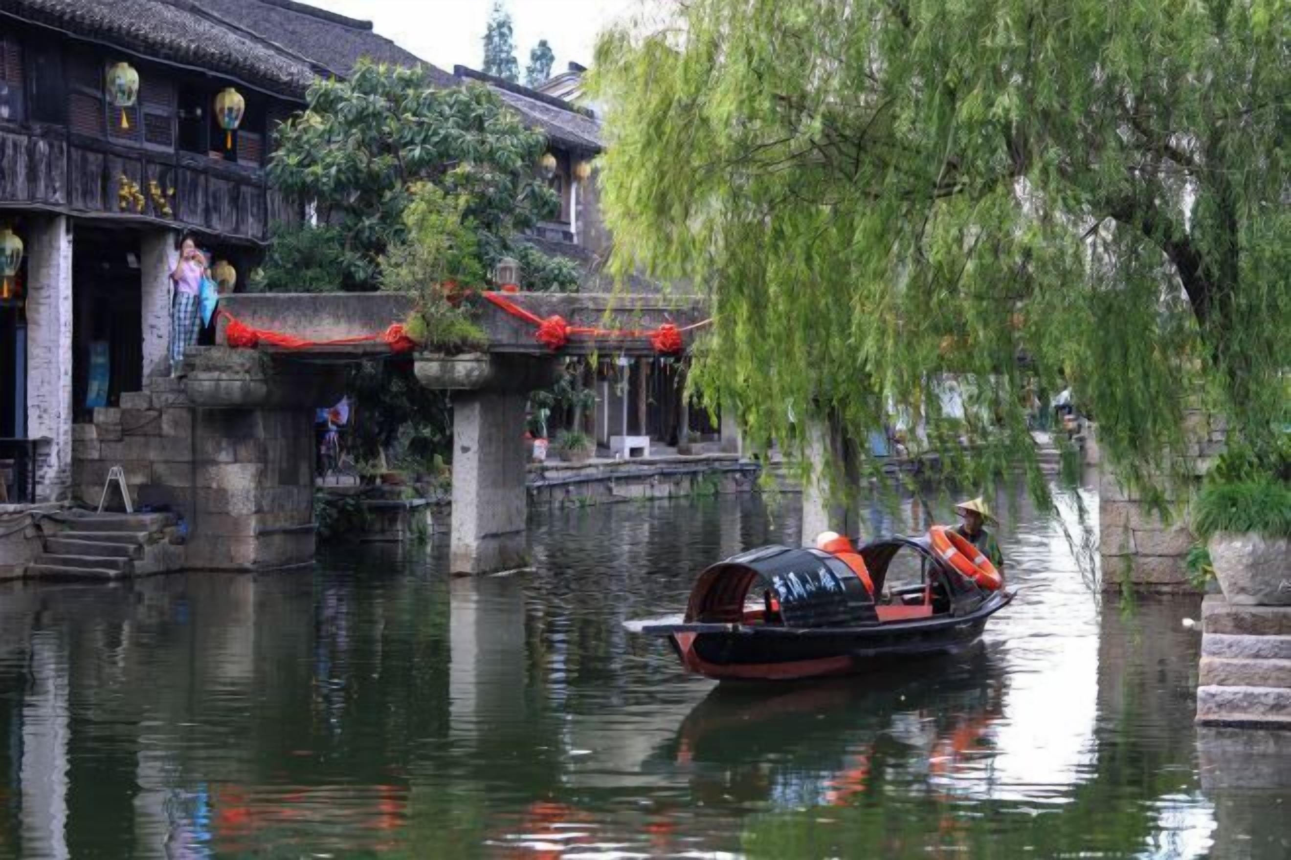 A traditional building with a thatched roof and a boat on the water.