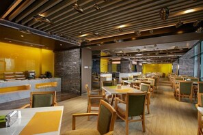 En moderne restaurant med flere borde og stole, en disk med kaffemaskine og en stenvæg.