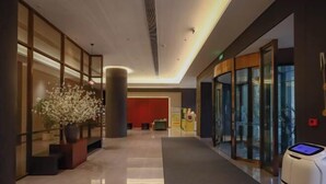 A modern hotel lobby with a reception desk, a large potted plant, and a self-service kiosk. - Pulun Hotel (Shaoxing Didang Shimao Plaza) (Shaoxing)