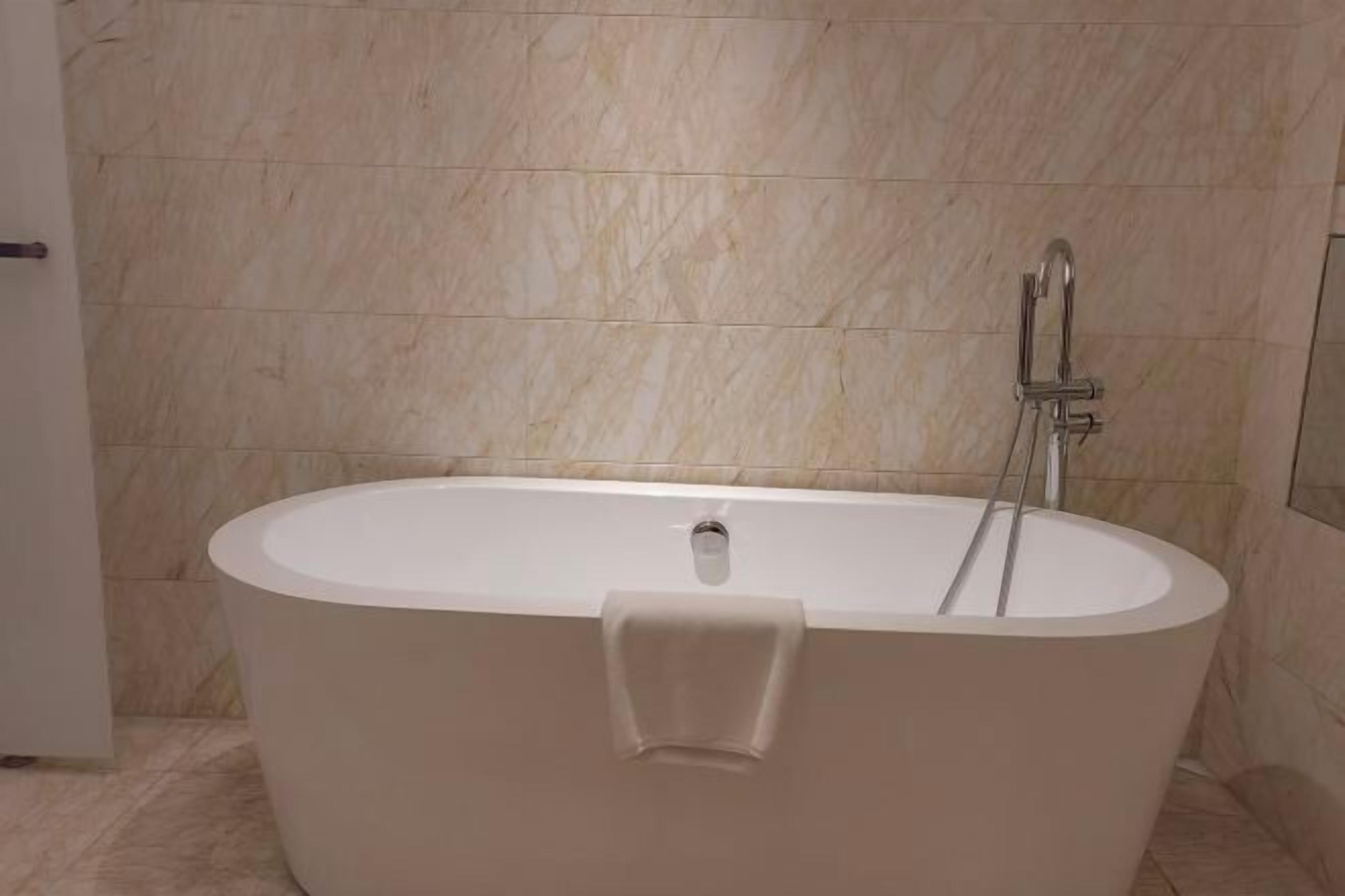 A modern bathroom with a freestanding bathtub, a handheld showerhead, and a towel rack.