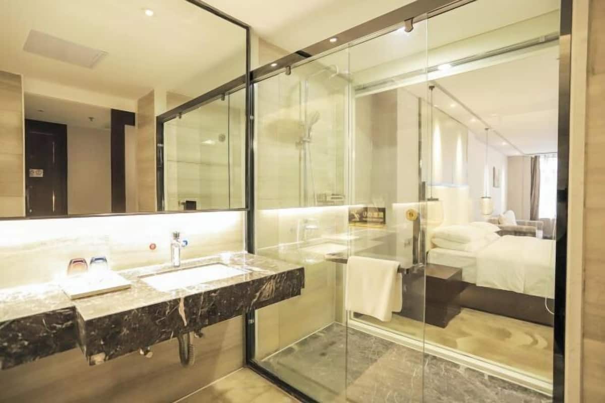 A modern bathroom with a glass shower enclosure, a marble sink, and a large mirror.