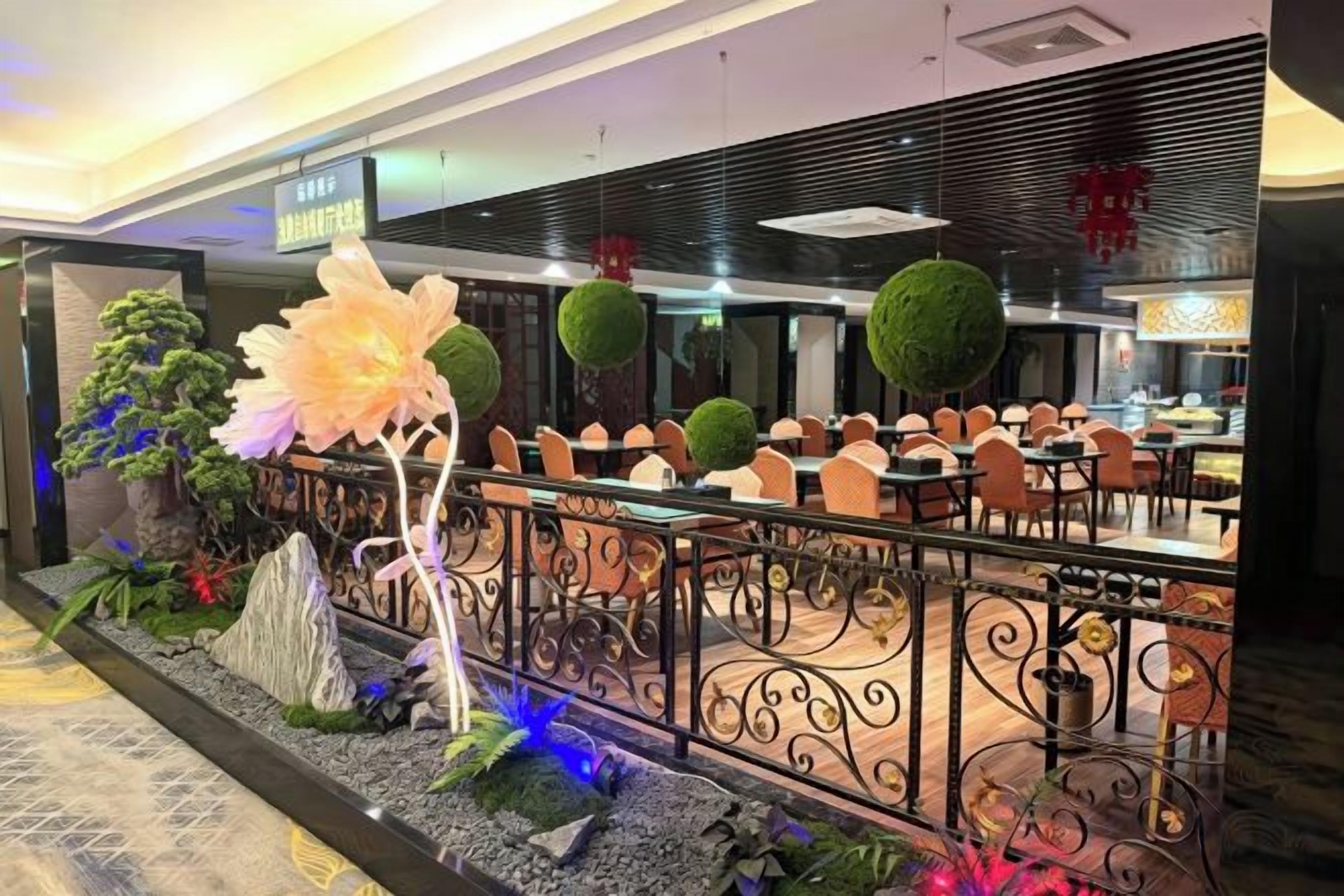 Un área de comedor con barandilla decorativa, plantas en macetas y un conjunto de asientos.