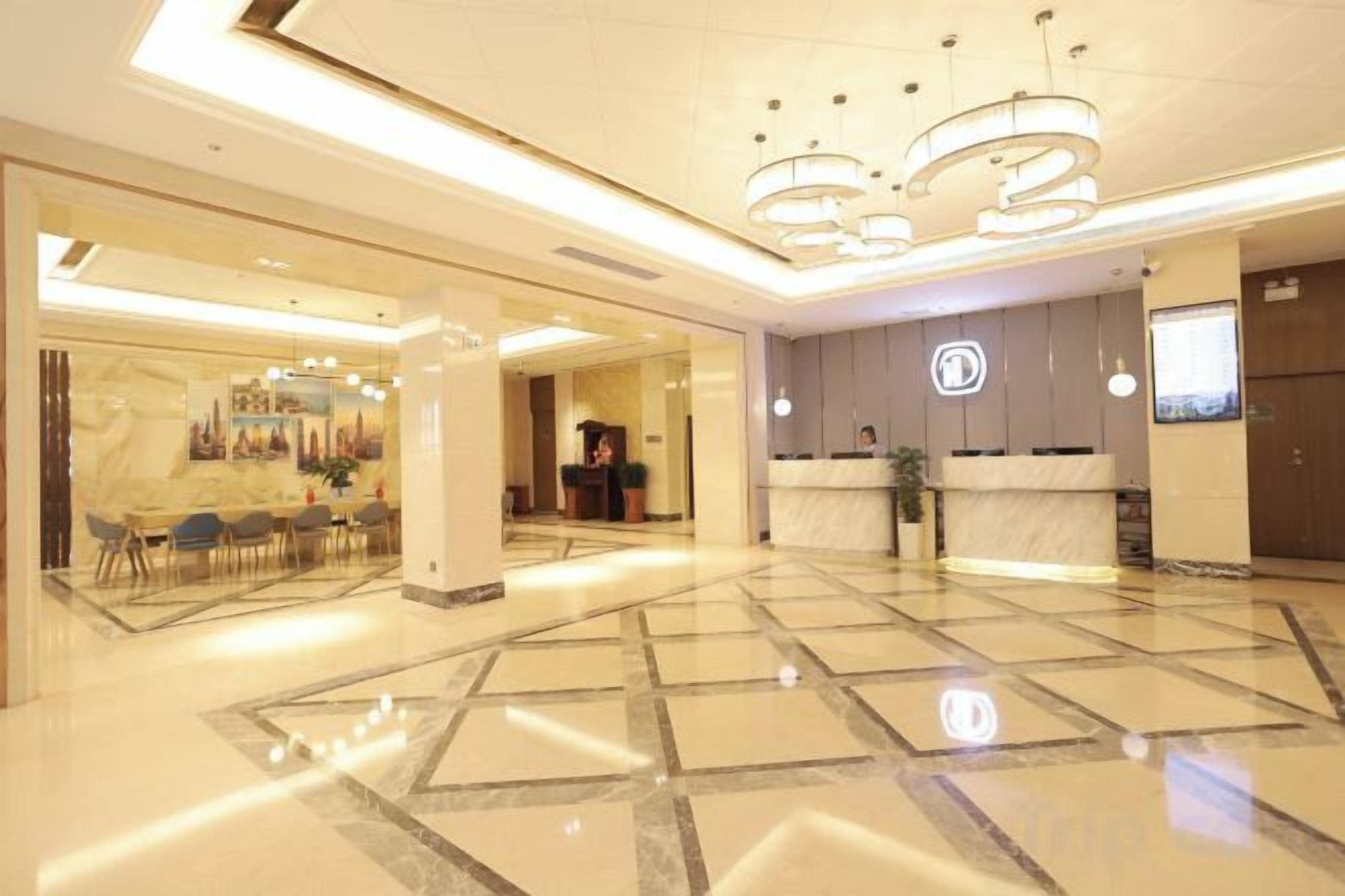 Un hall de hotel con mostrador de recepción, zona de estar y un amplio espacio abierto con suelo pulido.