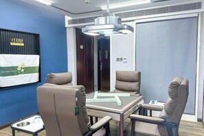 A conference room with a table and four chairs, a flag on the wall, and a door. - Huandu Around Capital Hotel (Shantou)