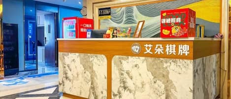 Un comptoir d’accueil doté d’un plateau en marbre et d’une structure en bois, agrémenté d’une enseigne avec des caractères chinois et d’une boîte rouge également ornée de caractères chinois.