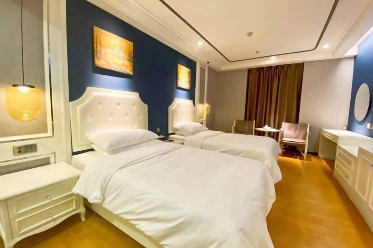 Une chambre d’hôtel avec deux lits, un bureau et une chaise.