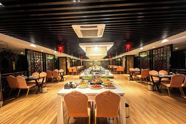 A restaurant with a long dining table, multiple chairs, and a modern ceiling design.