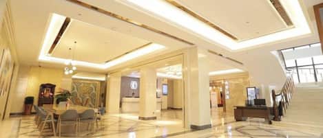 Un hall espacioso con una recepción, una escalera y un comedor.