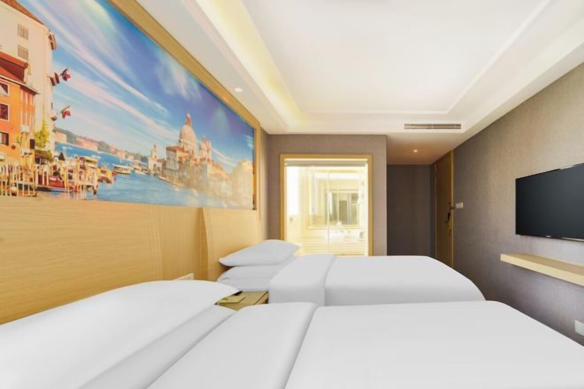 A hotel room with two beds, a painting of a cityscape, a television, and a window with a view of the city.