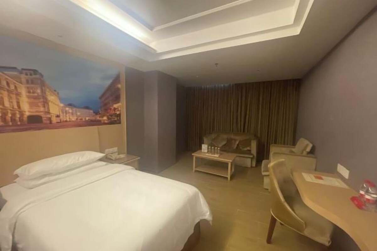 A hotel room with a bed, a desk, a chair, a sofa, and a large painting on the wall.