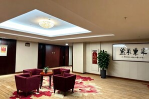 A hotel lobby with a skylight, seating area, and a reception desk. - Linyi Hotel (Development Zone) (Linyi)