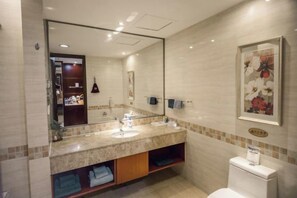 Ein Badezimmer mit großem Spiegel, zwei Waschbecken, Toilette und Handtuchhalter.