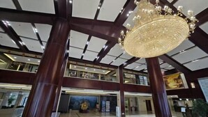 A spacious lobby with a high ceiling, large chandeliers, and a central decorative piece.