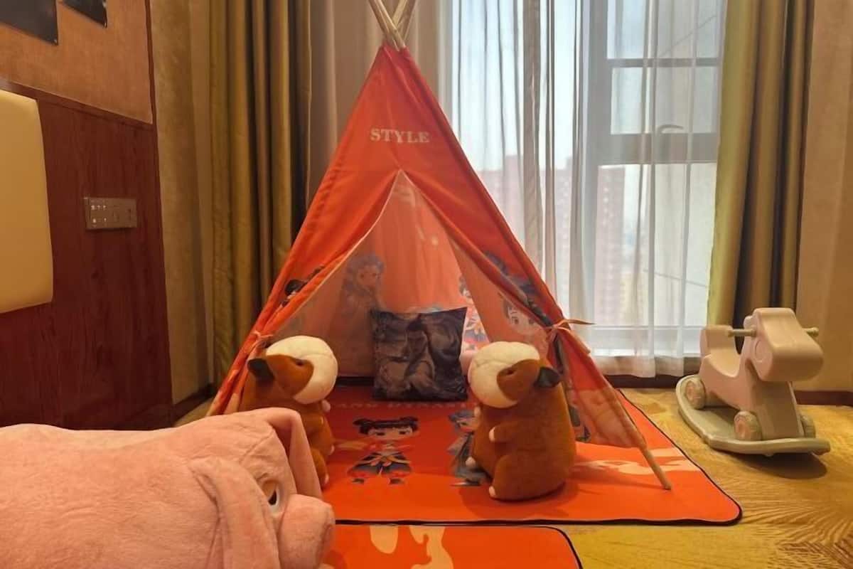 A room with a red tent-like structure, plush toys, and a toy car.