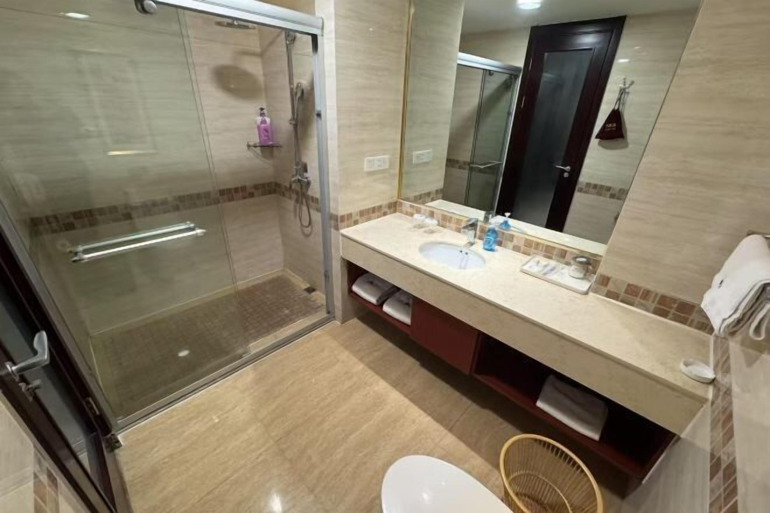 Une salle de bain avec une douche à parois de verre, un lavabo avec un miroir et des toilettes.