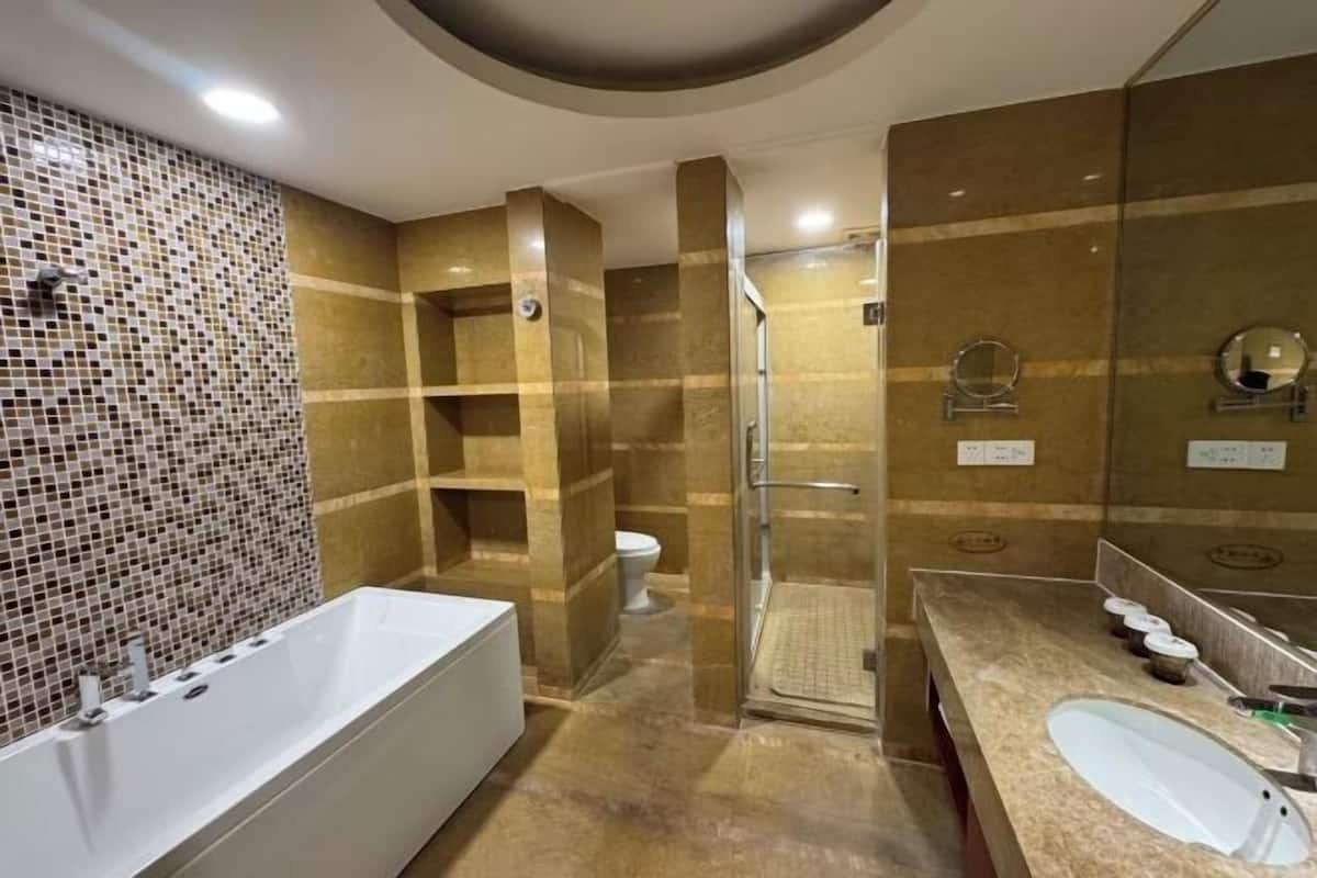 A modern bathroom with a large bathtub, a glass-enclosed shower, and a vanity with a sink and mirrors.
