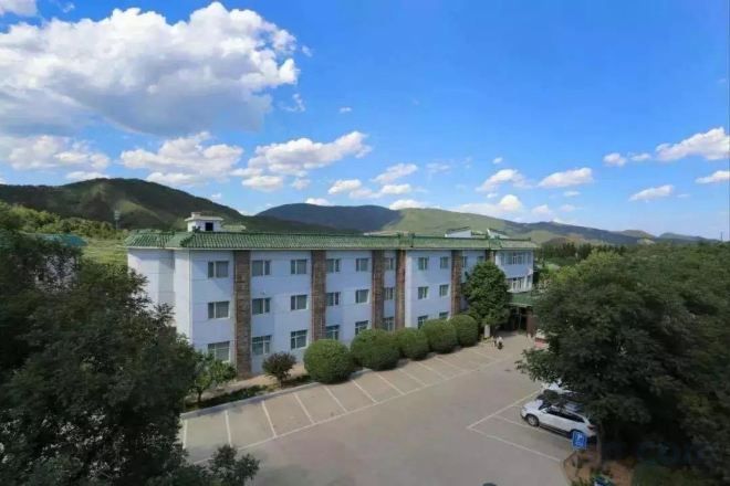 A multi-story hotel with a parking lot and a mountainous backdrop.