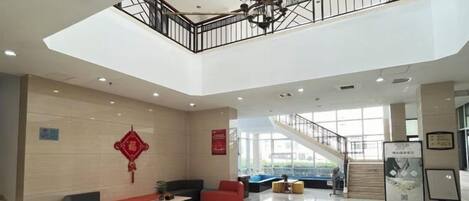 A spacious lobby with a high ceiling, a staircase, and seating areas.