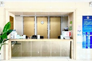 Una recepción con un reloj, una computadora y una planta.