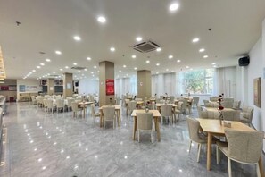 Un vaste espace de restauration intérieur, doté de nombreuses tables et chaises, de grandes fenêtres et d’un aménagement propre et moderne.