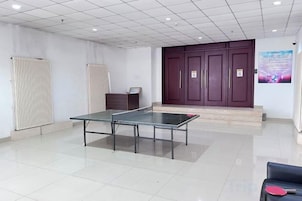 Una habitación con mesa de ping pong, un mueble oscuro y una puerta morada.