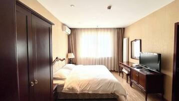 A hotel room with a bed, a TV, a wardrobe, and a desk.
