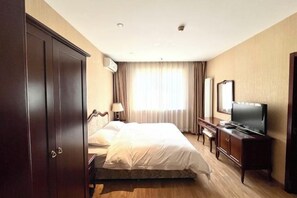 Ein Hotelzimmer mit Bett, Fernseher, Kleiderschrank und Schreibtisch.