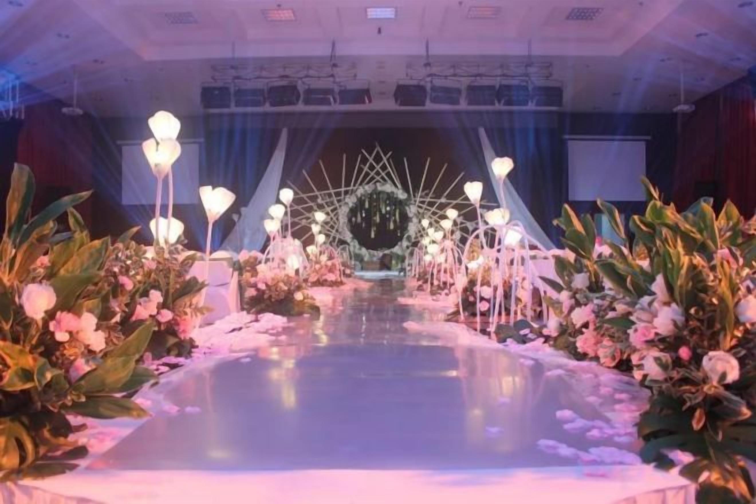 A stage with floral arrangements and a geometric backdrop.