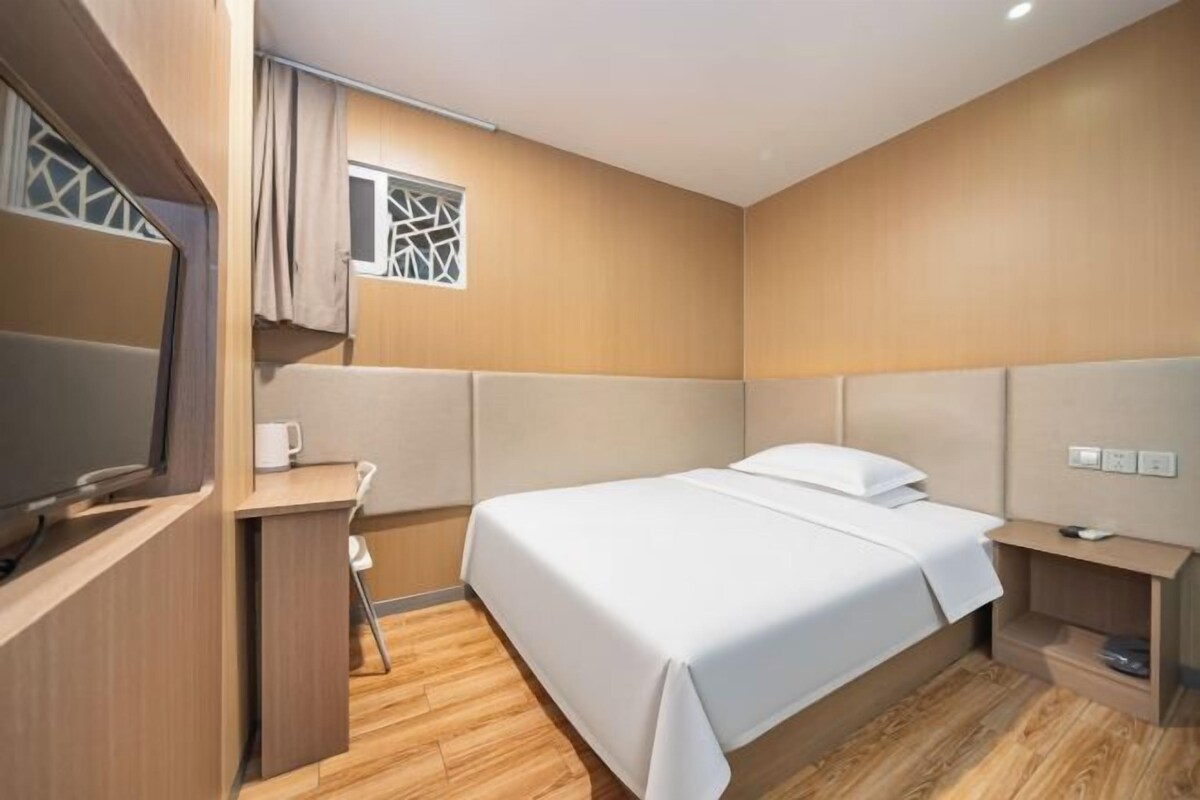 A compact bedroom with a bed, bedside table, and a small window.