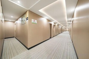 A hotel corridor with carpeted floors, beige walls, and doors on the right. - Ruyuan Select Hotel (Shanghai Pengpu Xincun Subway Station, Linfen Road Branch) (Shanghai)