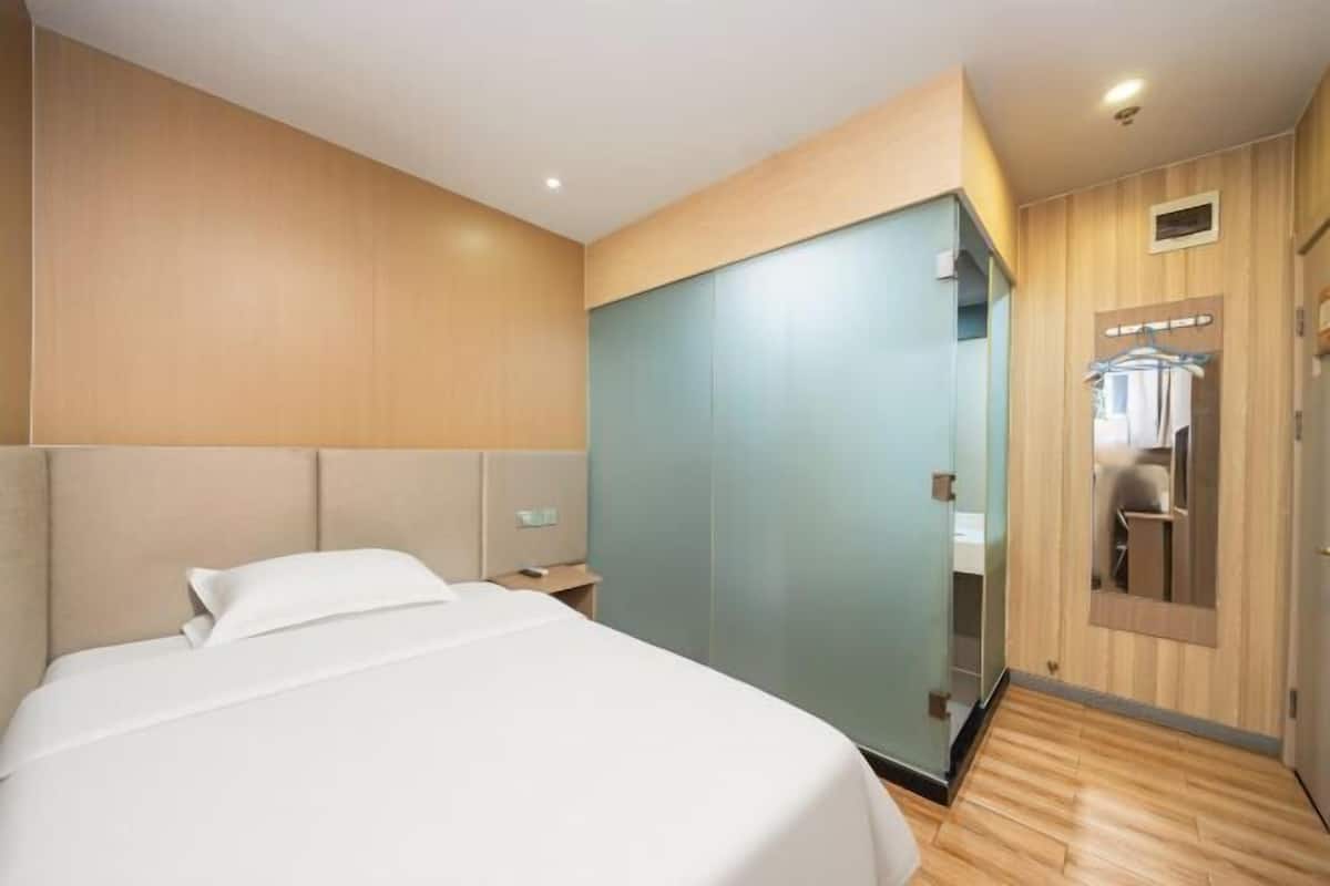 A hotel room with a bed, a wardrobe, a mirror, and a door.