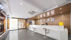 Zona reception di un hotel con scrivania in legno, tappeto rosso e insegna con caratteri cinesi.