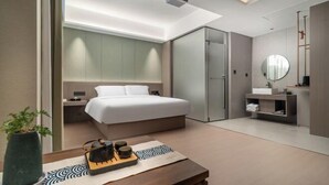Una habitación de hotel moderna con cama, mesita de noche y espejo.