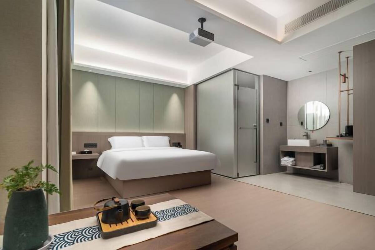 A modern hotel room with a bed, bedside table, and a mirror.