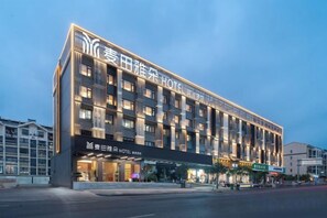 Et hotel i flere etager med en moderne facade, oplyst skiltning og en markant indgang.