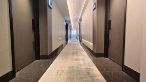 Un pasillo largo y estrecho en un hotel, con alfombra y paredes a ambos lados.