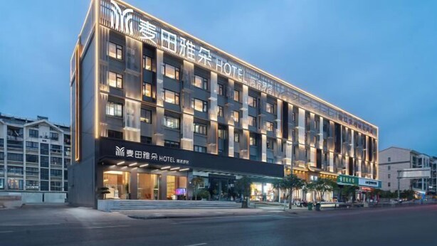 Un hotel moderno con un letrero llamativo, varios pisos y una entrada bien iluminada.