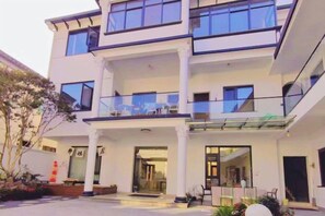 Un edificio de varios pisos con un vestíbulo cubierto, ventanas amplias y un balcón.