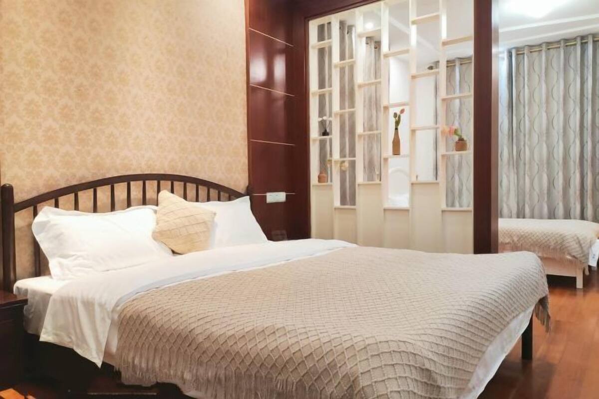 Ein Schlafzimmer mit einem großen Bett, einem Holzkopfstück, einem Nachttisch und einer eingebauten Regaleinheit mit dekorativen Gegenständen.