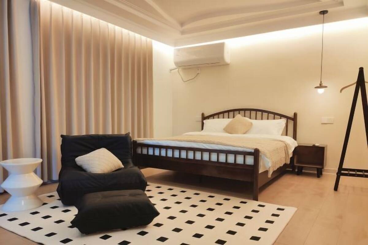 Ein Schlafzimmer mit Bett, Sessel, einem kleinen Tisch und einer Stehlampe.
