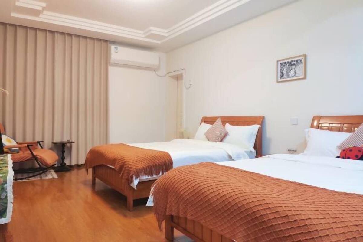 Ein Hotelzimmer mit zwei Betten, Holzboden, einem Sessel und einem kleinen Tisch.