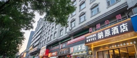A hotel with a prominent sign, outdoor seating, and a pedestrian walkway.
