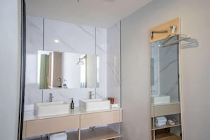A modern bathroom with two sinks, a large mirror, and a built-in shelf with a towel rack.