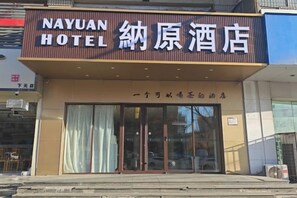 L'ingresso di un hotel con un cartello che recita 'NAYUAN HOTEL' e caratteri cinesi.