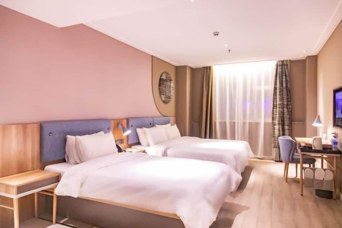 Une chambre d’hôtel avec deux lits, un bureau et une télévision.